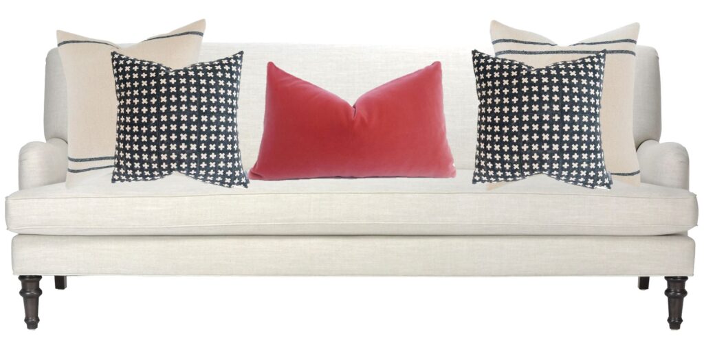 picture of a cream coloured traditional sofa with black and cream pillows and one coral velvet lumber pillow
